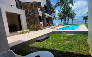 a house with a swimming pool next to the ocean at Canari Waterfront Villas in Roches Noires