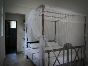 um quarto com uma cama de dossel com lençóis e almofadas brancos em Singha Holidays em Mirissa