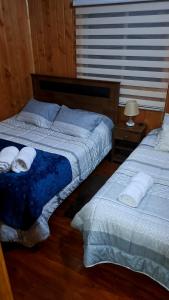 1 dormitorio con 2 camas y toallas. en Cabaña jazmin en Chaitén