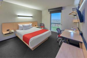 a hotel room with a bed and a desk and a table at City Express by Marriott Tijuana Insurgentes in Tijuana