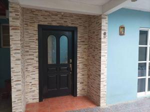 a black door on a brick wall at casa de mamá in Santa María Azompa