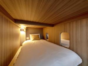 Iwasu-so في ناكاتسوجاوا: سرير أبيض كبير في غرفة بجدران خشبية