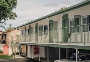 a building with a balcony with a car parked in front at The Cheshire Cat Motel in Gold Coast