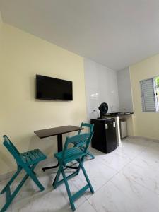 Zimmer mit 2 Stühlen, einem Tisch und einem TV in der Unterkunft Kitnet privada confortável em Pontal do Sul in Pontal do Paraná