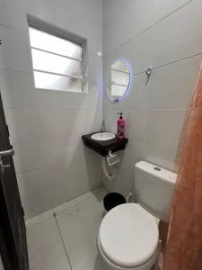 a white bathroom with a toilet and a sink at Kitnet privada confortável em Pontal do Sul in Pontal do Paraná