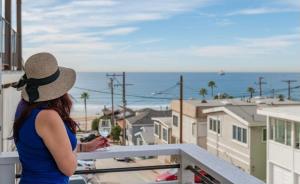 een vrouw op een balkon met uitzicht op de oceaan bij Amazing location! Luxurious beach cottage.Ocean views in Manhattan Beach