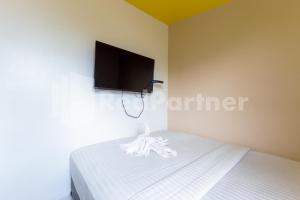 um quarto com uma cama e uma televisão de ecrã plano na parede em Ichiza Room RedPartner em Jakarta