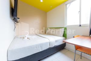 a small bedroom with a bed and a desk at Ichiza Room RedPartner in Jakarta