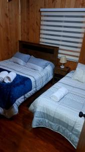 dos camas sentadas una al lado de la otra en un dormitorio en Cabaña jazmin en Chaitén
