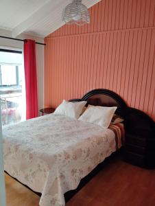 1 dormitorio con 1 cama con pared roja en Cabañas Catalina 5, en Tomé
