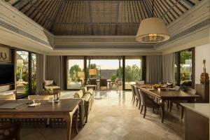 a dining room with tables and chairs and windows at Jumeirah Bali in Uluwatu