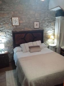1 dormitorio con 1 cama grande y pared de piedra en La Remulla, en Paüls