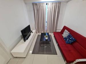 a living room with a red couch and a tv at AZ Apartment @ Cyberjaya Netflix Wi-Fi in Cyberjaya