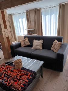 a living room with a black couch and a table at Résidence Gavarnie appart RDC in Gèdre