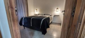 Un dormitorio con una cama con una manta negra. en Cabañas Mailen'S en Puerto San Julián