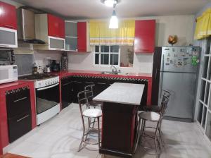 cocina con armarios rojos y blancos y nevera en Casa de mamá en Santa María Azompa