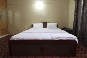 a bedroom with a large bed with white sheets and pillows at Hotel Gulfam Palace in Pahalgām