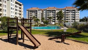 un parque infantil frente a un complejo de apartamentos con piscina en Departamentos Heimat 3 en La Serena