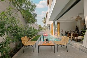 un patio con tavolo, 2 sedie e piscina di The Banyan Tree Villa A4 by Stay ALYF, Siolim a Siolim
