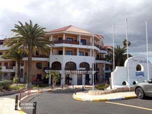 a large white building with palm trees in a parking lot at Las Meninas Tenerife in San Miguel de Abona