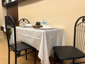 a table with a white table cloth and two chairs at Stylish Iloilo condo w/ Netflix and pool access in Iloilo City +2 photos