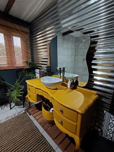 a bathroom with a yellow sink and a mirror at Fire Fly Cabin in Knysna