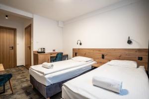 a hotel room with two beds and a desk at Pirat Hotel & SPA-hotel z basenem in Olsztyn