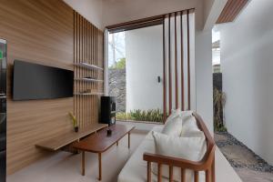a living room with a white couch and a tv at Lodji Ubud in Ubud