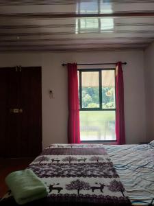 a bedroom with a bed and a window with red curtains at ExoticaHolidays in Sultan Bathery