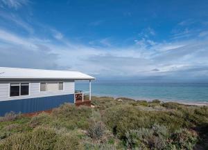 a house on the beach with the ocean in the background at Ceduna Shelly Beach Caravan Park in Ceduna