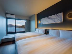 a bedroom with two beds and a large window at Rakuten STAY FUJIMI TERRACE 箱根芦ノ湖　 in Moto-hakone