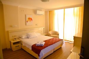 um quarto de hotel com uma cama e uma janela em Nagidos Hotel em Bozyazı