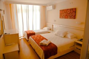 a hotel room with two beds and a window at Nagidos Hotel in Bozyazı