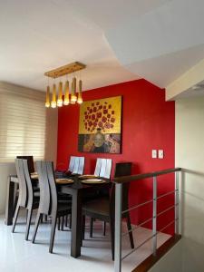 una sala da pranzo con tavolo e parete rossa di Richwell de Maison at Pontefino Prime Elite a Città di Batangas
