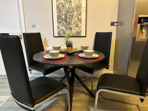 een eettafel met stoelen en een tafel met kopjes en borden bij *Luxury 9ine Lush Jacuzzi Apartment & Balcony* in Birmingham