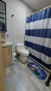 baño con aseo y cortina de ducha azul y blanco en Casa Vacacional en Condominio Via Melgar-Carmen de Apicalá, en Melgar