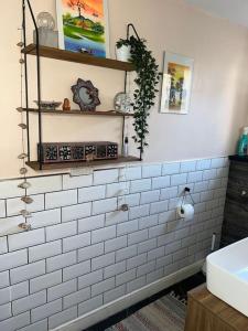Ivy Villa في Trench: حمام به جدران من البلاط الأبيض ومغسلة