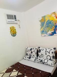 Habitación con sofá con almohadas y ventilador. en Queen's Room Rental 4 en El Nido