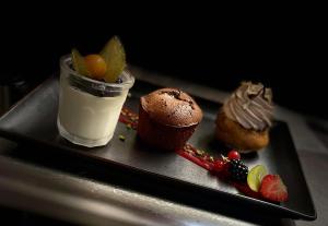 a black plate with desserts and a drink on it at Logis Le Relais Saint Jacques in Saint-Léonard-de-Noblat
