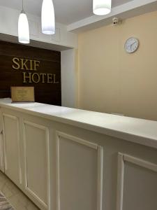 a reception desk in a hotel with a clock on the wall at Skif Hotel in Astana