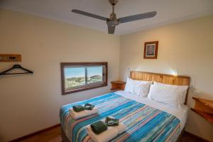 Ceduna Shelly Beach Caravan Park في سيدونا: غرفة نوم بسرير وفوط ونافذة