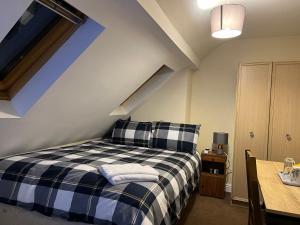 a bedroom with a black and white plaid bed at HAMS LODGE - - Strictly Only ONE GUEST ALLOWED IN ONE ROOM A SECOND ACCOMPANYING PERSON WILL NOT BE ALLOWED INTO THE PROPERTY in Birmingham