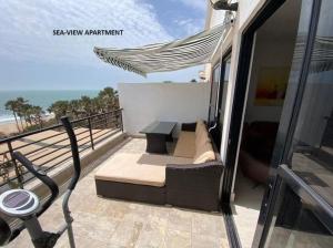 a balcony with a couch and a table and the beach at Luxury & Comfort, with Pool and Ocean Views in Bijilo