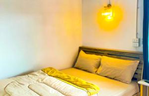 a room with a bed with yellow sheets and pillows at Nam Hu Camping น้ำฮูแคมป์ปิ้ง in Chiang Dao