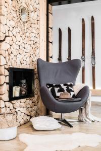 a chair in a living room with a stone wall at Villa 11 Folk & Design in Zakopane