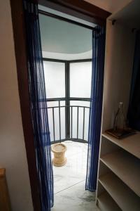 an open door to a balcony with blue curtains at Twinn Waves Calicut in Kozhikode