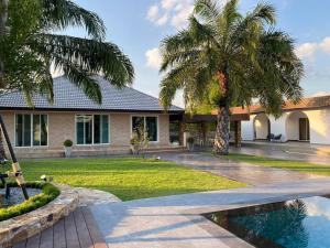 a house with palm trees and a swimming pool at Arom Pool Villa Pattaya 2 in Na Jomtien
