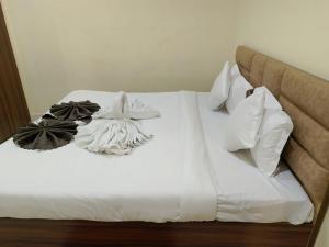 - un lit avec des draps et des oreillers blancs dans l'établissement Hotel Raipur Pride, à Raipur