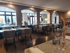 a dining room with tables and chairs and windows at Hotel-Restaurant Ammertmann in Gronau
