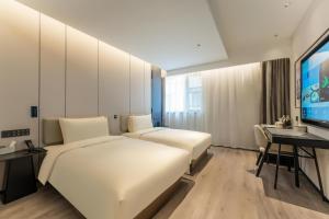 a hotel room with two beds and a flat screen tv at Atour Hotel Shanghai Xintiandi Metro Station in Shanghai